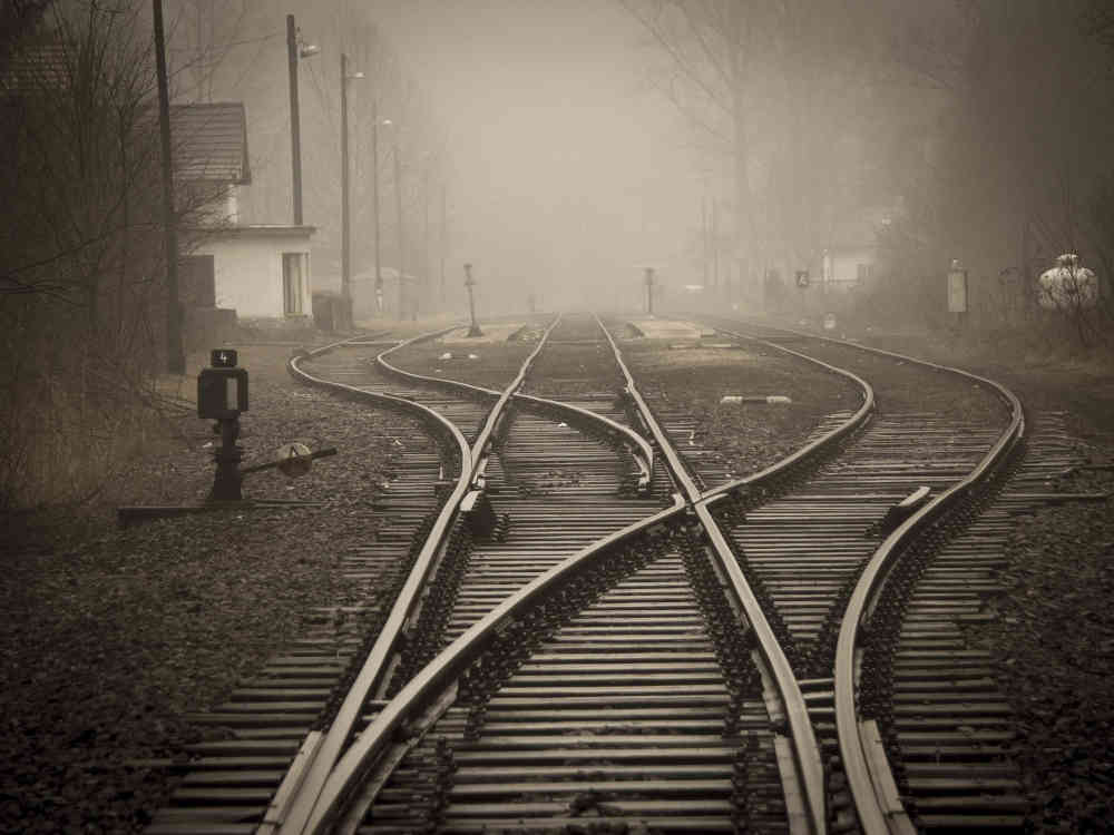 Looking down railway tracks that disappear in the distance and mist, with points in foreground.